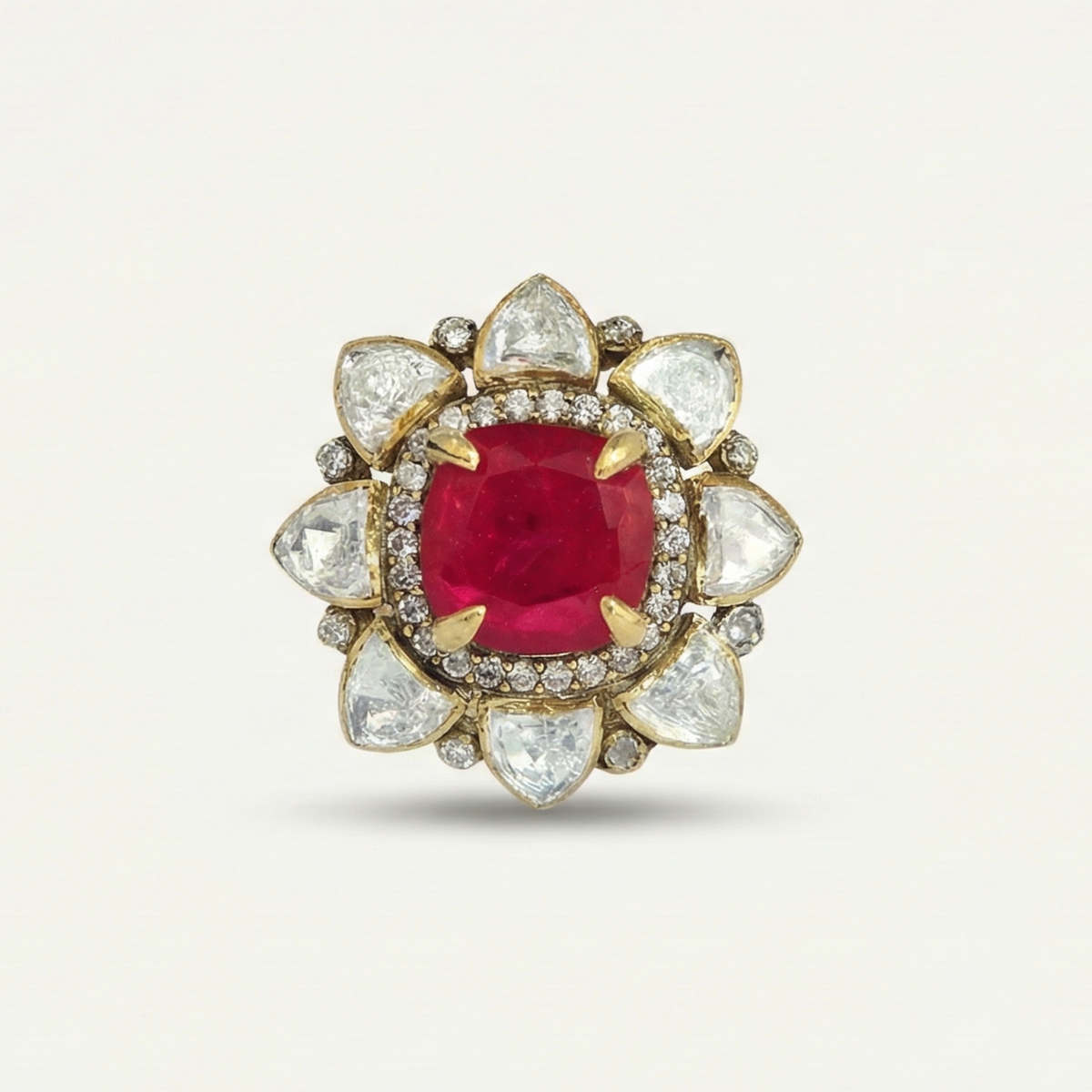 Gold ring with a red gemstone and diamond-studded band on a white background